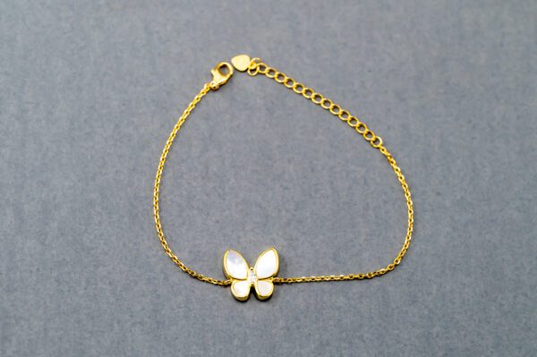 A gold bracelet with a butterfly on it.