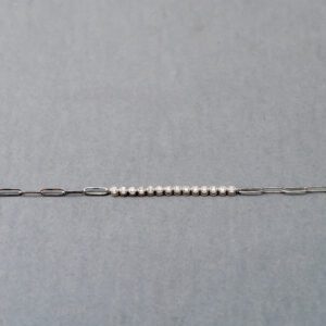 A silver chain with white beads on it.
