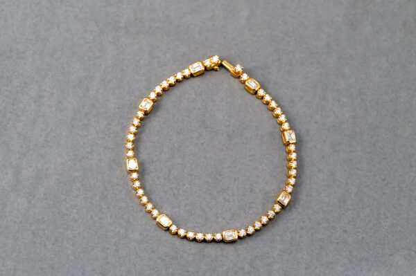 A gold bracelet with small beads and tiny squares.
