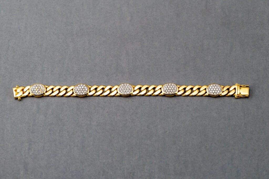 A gold chain with five oval shaped diamonds on it.