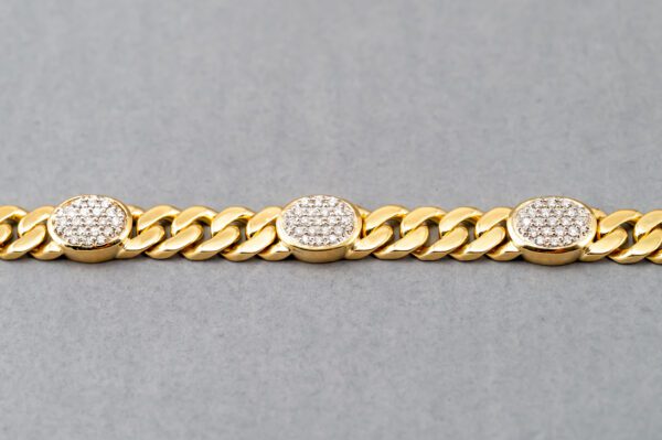 A gold chain with three oval shaped diamonds on it.