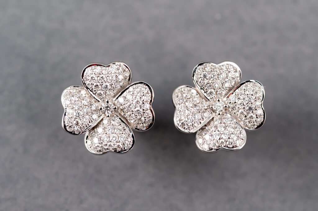 A pair of earrings with four leaf clover shaped diamonds.