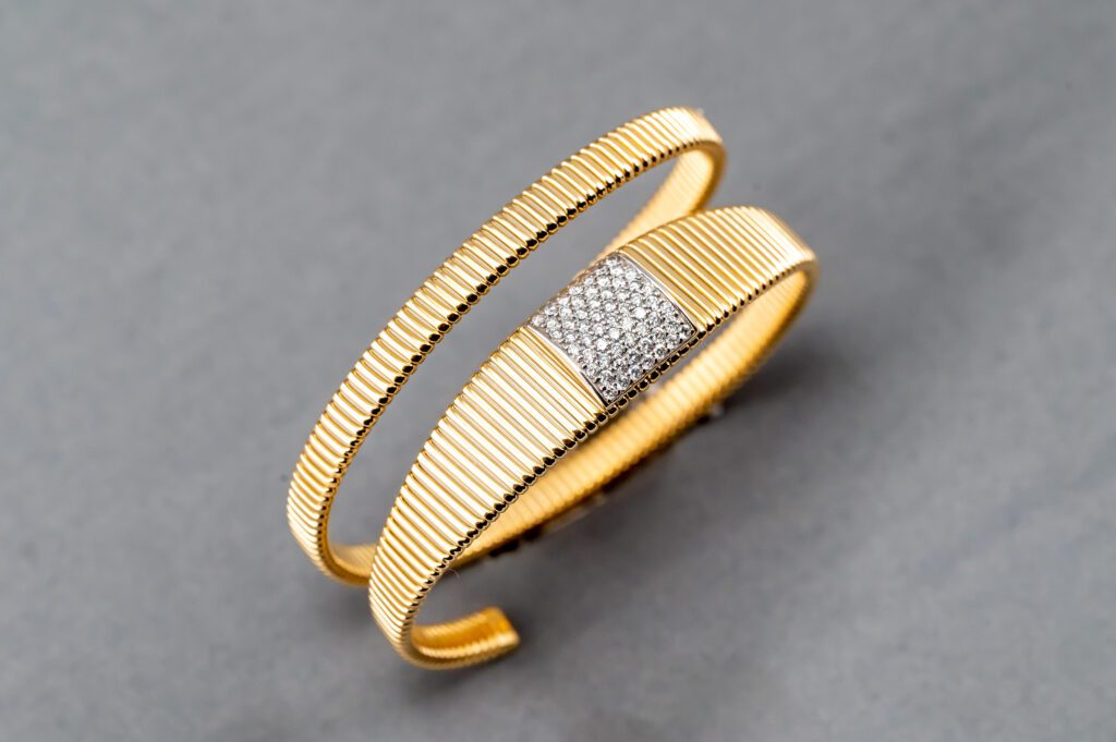 A gold bracelet with diamonds on it's side.