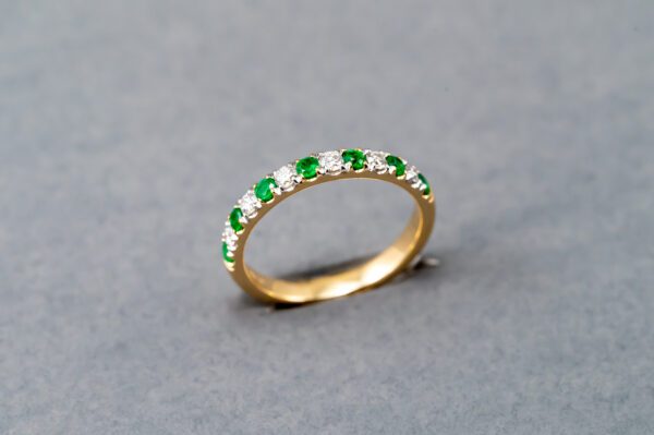 A gold ring with green and white stones.