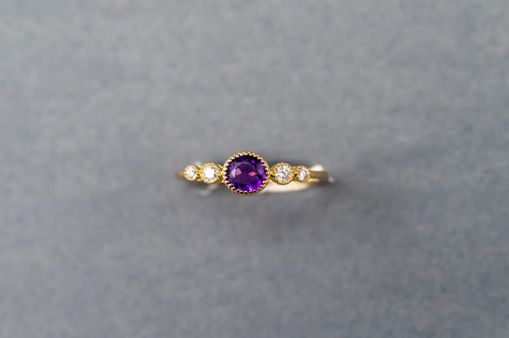 A gold ring with purple stone and small diamonds.