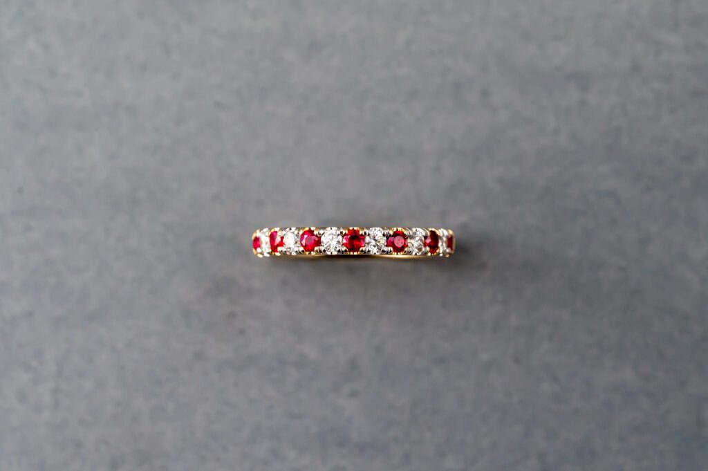 A red and white diamond band ring on a gray surface.