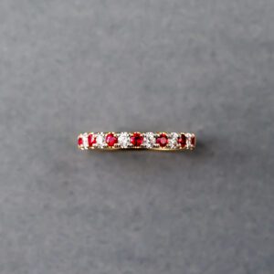 A red and white diamond band ring on a gray surface.