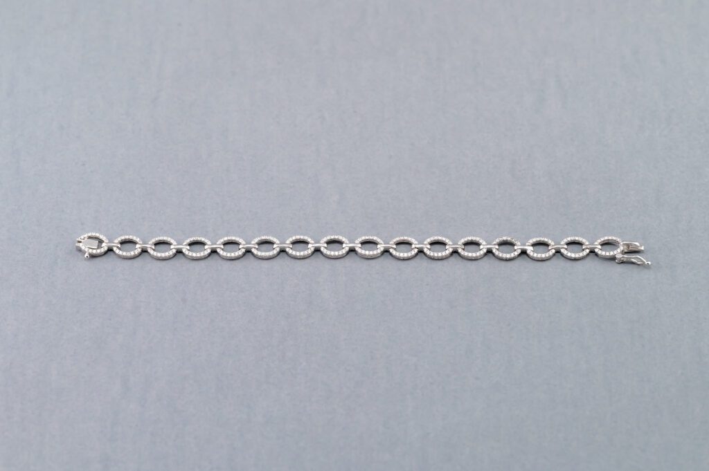A chain of silver colored oval links on a gray background.