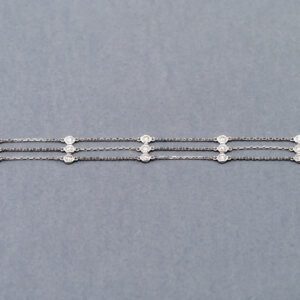 A silver chain with three white beads on it.