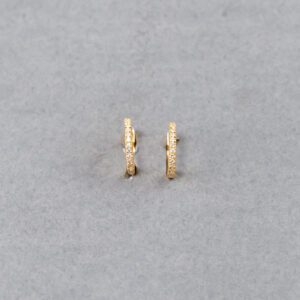 A pair of gold earrings sitting on top of a gray surface.