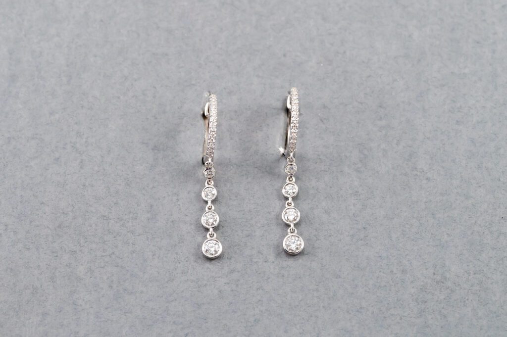 A pair of earrings with three diamonds hanging from them.