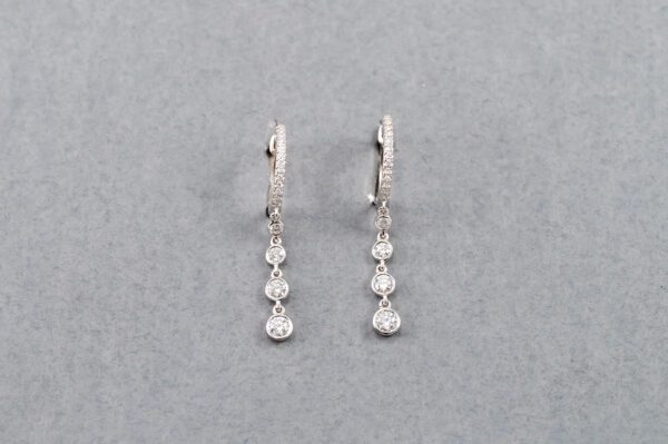 A pair of earrings with three diamonds hanging from them.