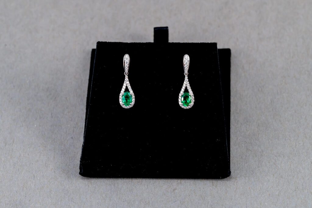 A pair of earrings with green stones on top of black velvet.