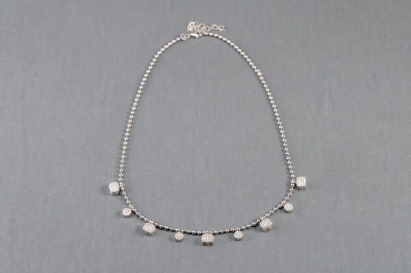 A silver necklace with small white beads on it.