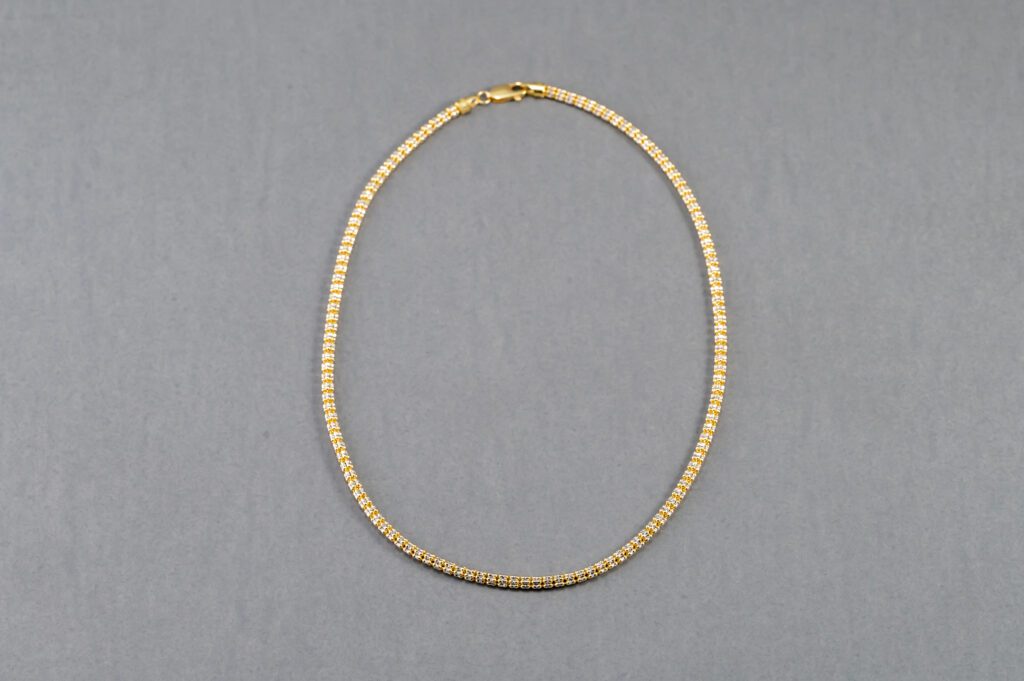 A gold chain necklace on a gray background.