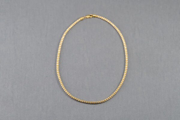 A gold chain necklace on a gray background.