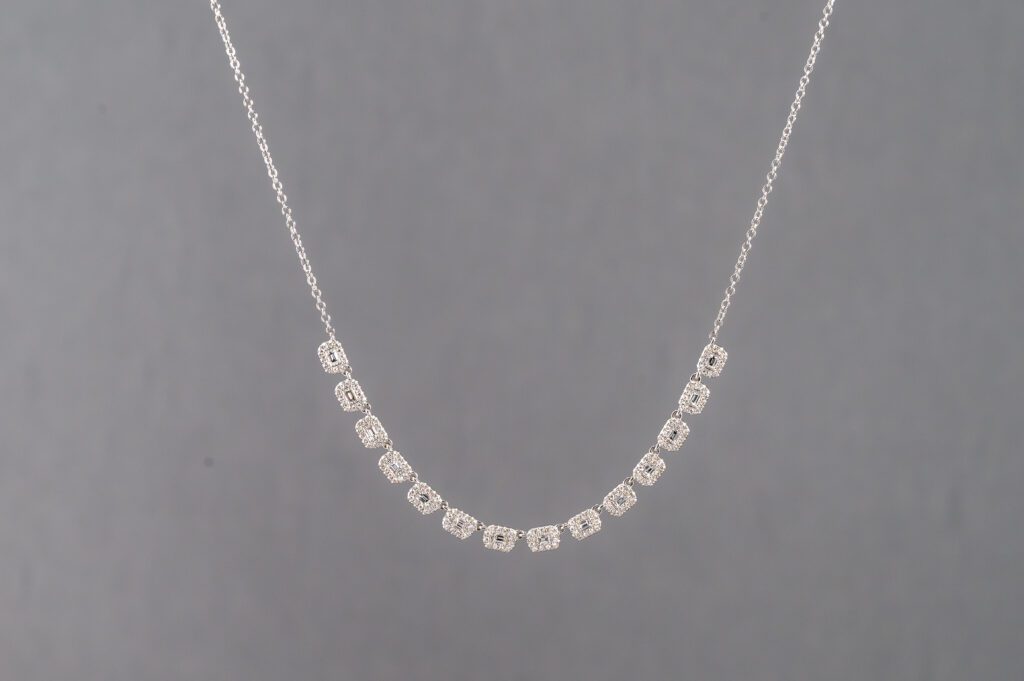 A silver necklace with a number of small squares.