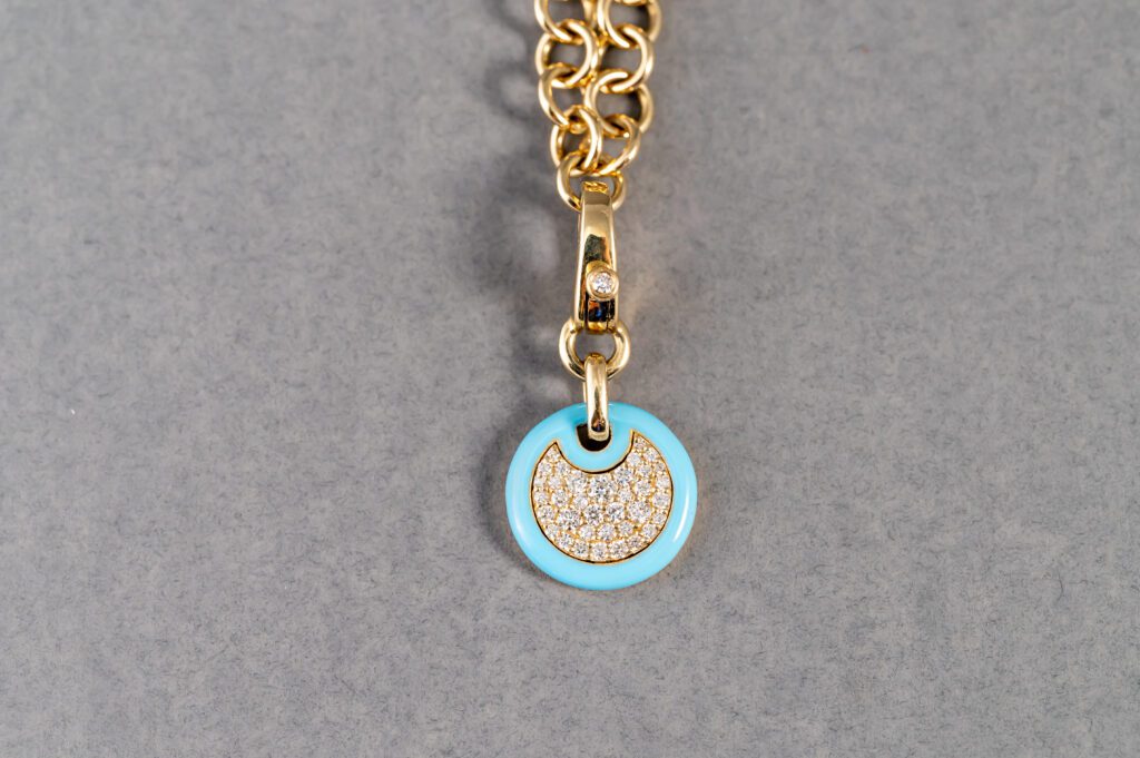 A gold chain with a blue charm on it.