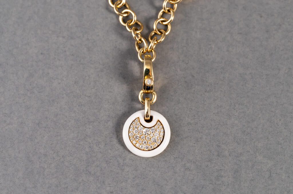 A gold chain with a white pendant on it.