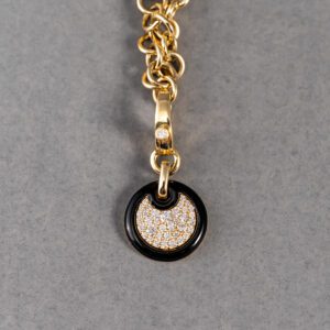 A gold chain with a black and white pendant on it.