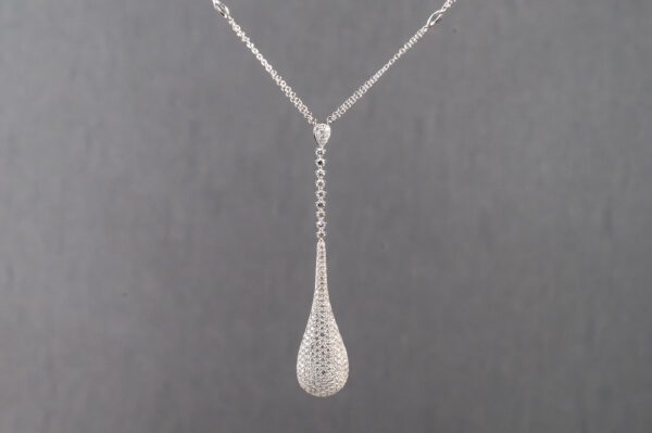 A silver necklace with a long chain and a drop shaped pendant.