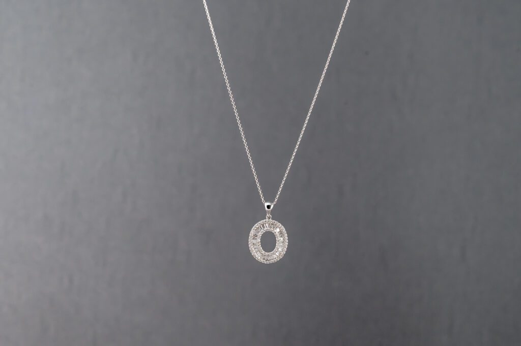 A silver necklace with an open circle on it.