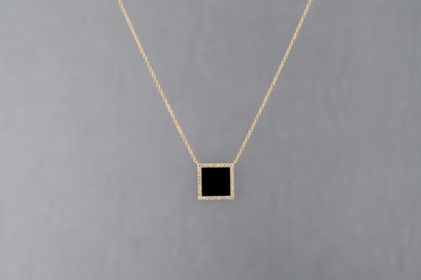 A square black stone with gold frame on chain.