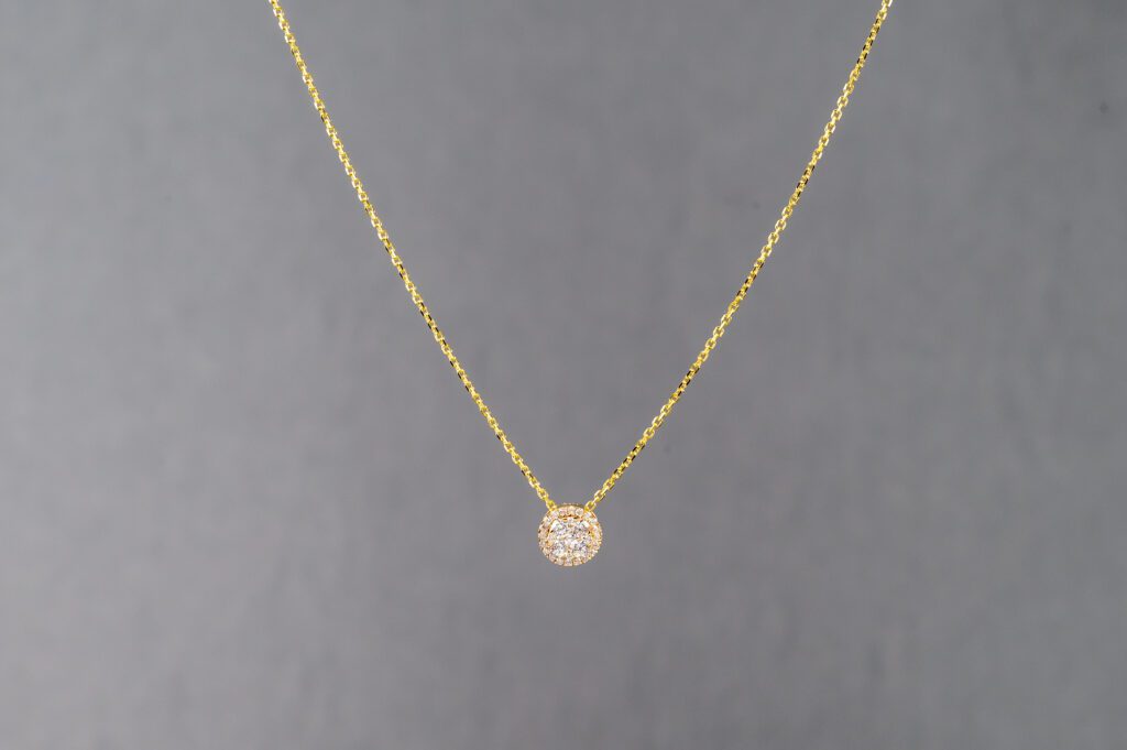 A gold necklace with a small diamond on it.
