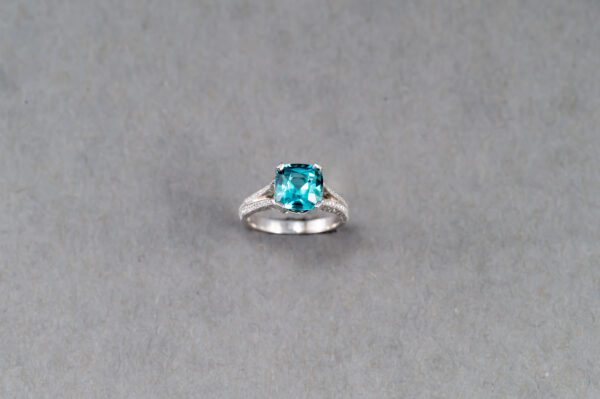 A blue stone is sitting on top of a silver ring.