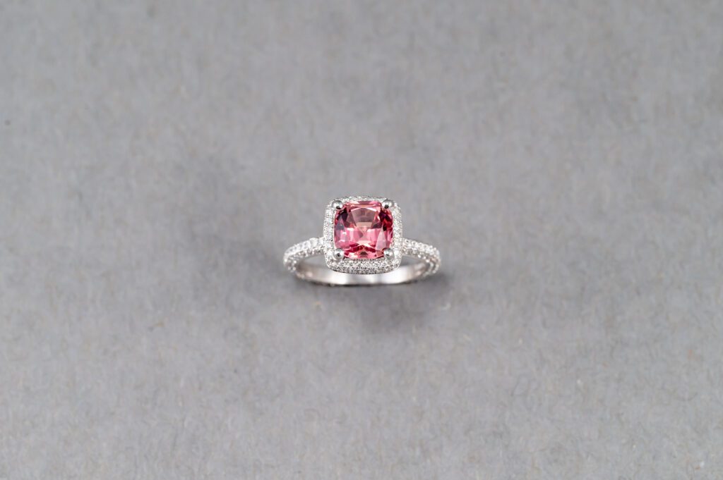 A pink stone is sitting on top of a silver ring.