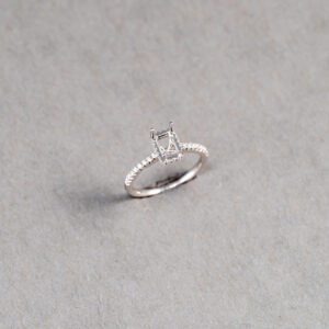 A silver ring with an emerald cut diamond.