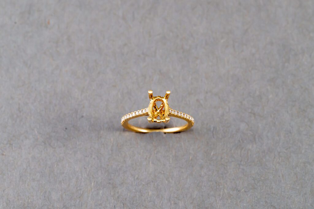 A gold ring with an oval cut diamond on it's side.