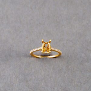 A gold ring with an oval cut diamond on it's side.