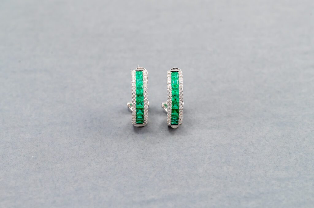 A pair of green earrings on top of a white surface.